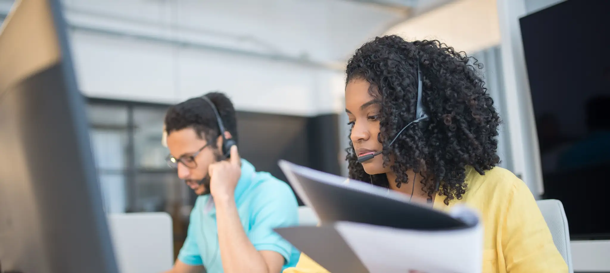 Two Backpack support team members wearing headsets, working at their desks