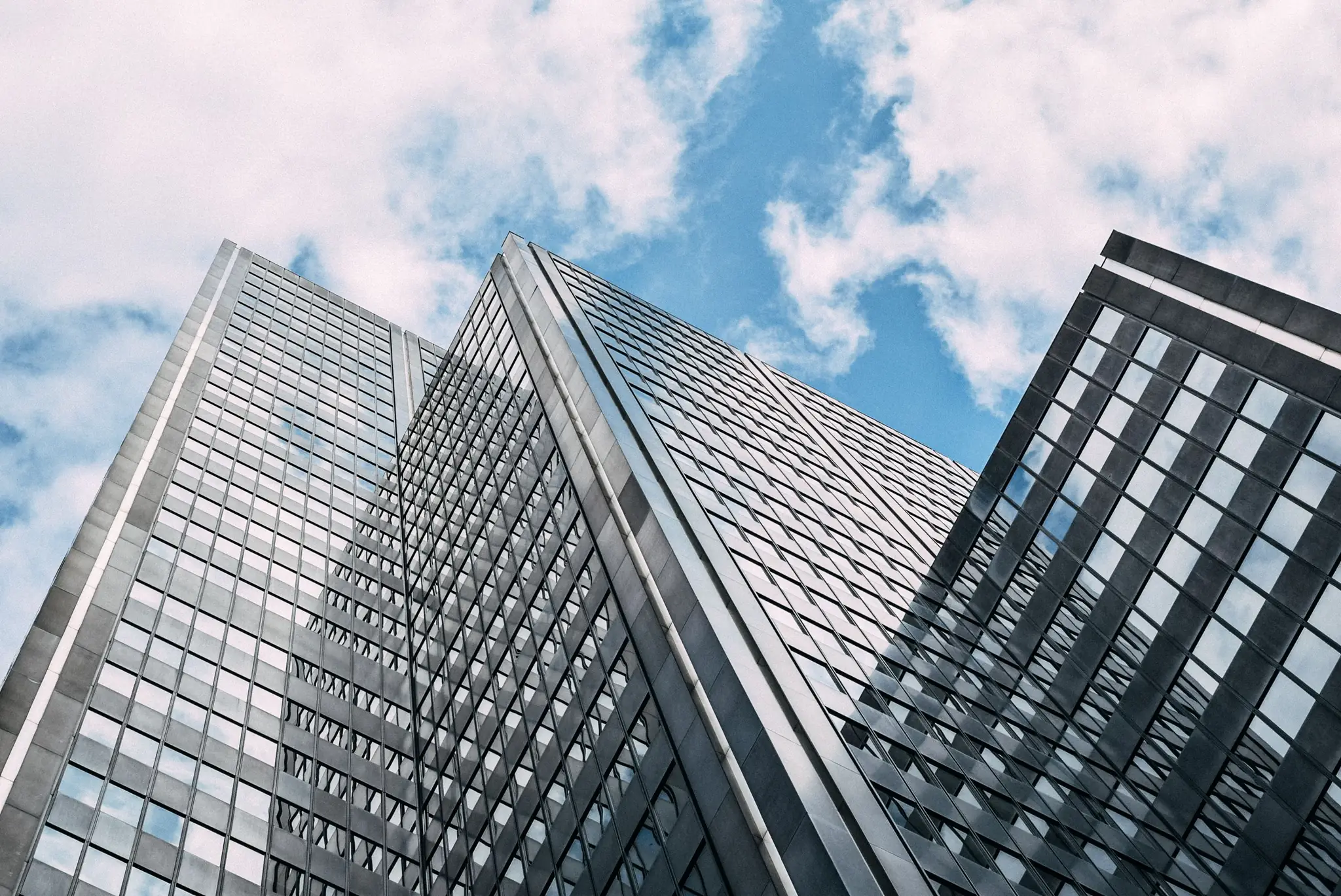 Glass office towers rising into a cloudy sky